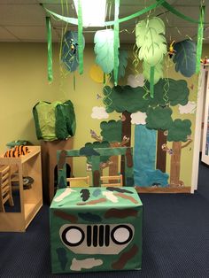 an office decorated in green and brown with a camouflage jeep themed chair cover, trees, and paper streamers hanging from the ceiling