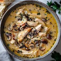 chicken and mushroom soup in a bowl with bread on the side, ready to be eaten