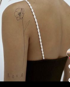 the back of a woman's shoulder with a single flower tattoo on her left arm