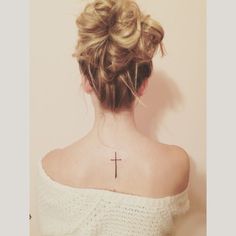 a woman with a cross tattoo on her upper back neck and behind her head is a white sweater