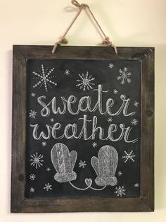 a chalkboard sign that says sweater weather with mittens and snowflakes on it