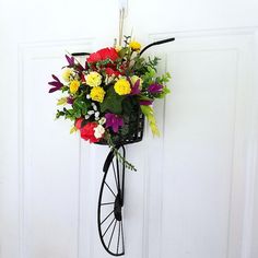 a bunch of flowers hanging on the side of a white door with a wheel attached to it