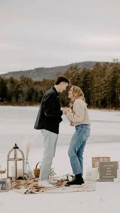 a man and woman standing next to each other on top of a snow covered field