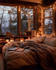 an unmade bed sitting in front of a window with lights on the windowsill