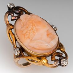 This captivating Art Nouveau ring features 1 angel skin carved cameo and 4 old mine cut diamonds. This ring is crafted of 10k yellow gold and is currently a size 3.5. We left the ring unpolished with a lovely rich natural patina. One of the diamonds has a chip but nothing distracting. Antique Diamond Intaglio Jewelry, Art Deco Oval Cameo Rings, Art Deco Cameo Ring For Collectors, Art Deco Cameo Ring Collectible, Art Deco Cameo Collectible Rings, Antique Carved Wedding Rings, Art Nouveau Yellow Gold Intaglio Jewelry, Victorian Carved Wedding Rings, Art Deco Carved Rings For Wedding