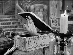 a person holding a book in their hands while sitting at a table with candles on it