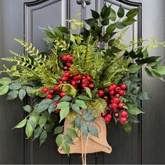 a wreath with berries and greenery hanging on a door