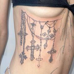 a woman's stomach with tattoos on it and rosarys attached to the side