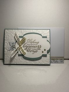 a white card with a cross on the front and words written in gold foiling