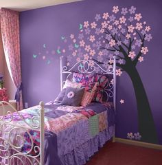 a bedroom decorated in purple and pink with a tree painted on the wall