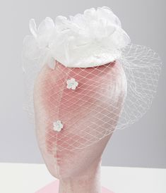 An elegant white sinamay fascinator boasts a stunning cascading mesh florals and birdcage veil. Set on a white satin fascinator, secured with dual alligator clips. Available while supplies last. Adjustable Tulle Fascinator For Wedding, Adjustable Tulle Wedding Fascinator, Tulle Fascinator For Royal Ascot, White Fitted Veil For Formal Occasions, Formal Fitted White Veil, Fitted Tulle Hats For Weddings, Elegant Tulle Mini Hats For Wedding, White Tulle Bridal Accessories For Evening, White Spring Ceremony Headpiece