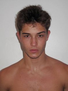 a young man with no shirt on posing for the camera in front of a white wall