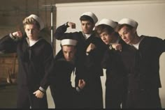 five young men in sailor's outfits posing for a photo together, with one pointing at the camera