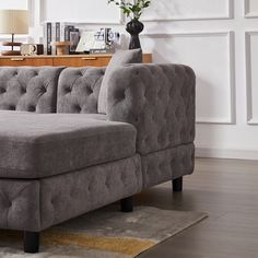 a gray couch sitting on top of a wooden floor next to a lamp and table