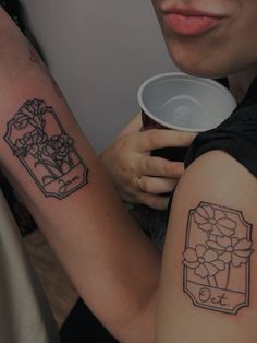 a woman holding a cup with tattoos on her arm