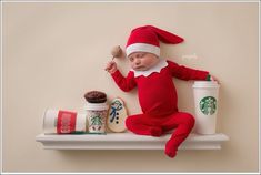 a baby dressed as santa claus is sleeping on a shelf with starbucks cups and cookies