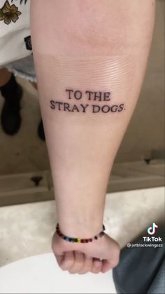 a person with a tattoo on their arm that says to the stray dogs