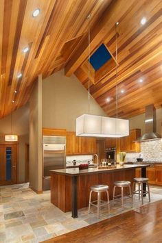 a kitchen with wooden ceiling and tile flooring next to an island in the middle