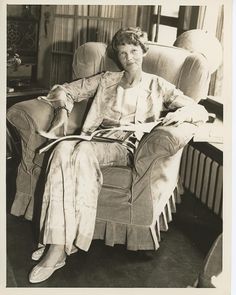 an old black and white photo of a woman sitting in a chair