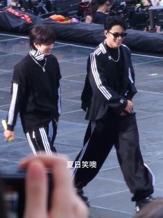 two young men walking down a street next to each other