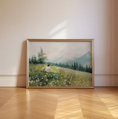 a painting is sitting on the floor in front of a white wall and wooden floors