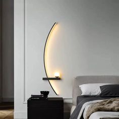 a bedroom with a bed, night stand and lamp on the wall next to it