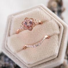 two gold rings with pink and white diamonds on them sitting in a velvet ring box