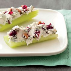 two pieces of celery with cream cheese and cranberries on it sitting on a white plate