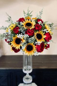 a bouquet of sunflowers and roses in a clear glass vase on a table