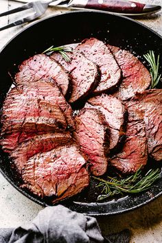 steak in a skillet with rosemary on the side