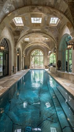 a large indoor swimming pool with an arched ceiling and skylight above it is surrounded by windows