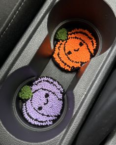 two halloween decorations are placed in the center of a car seat belt holder, which is decorated with pumpkins and jack - o - lantern faces