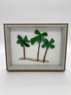 two palm trees in a shadow box with sand underneath them and the bottom half is white