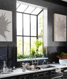 a kitchen with black cabinets and white counter tops is featured in the article, herbs are planted in the base of the solar - style window