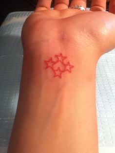 a small red star tattoo on the wrist