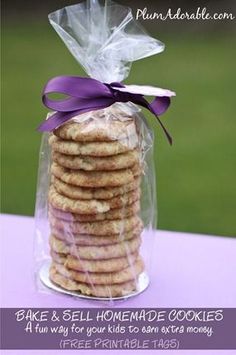 a stack of cookies wrapped in plastic on top of a purple tablecloth with a purple ribbon