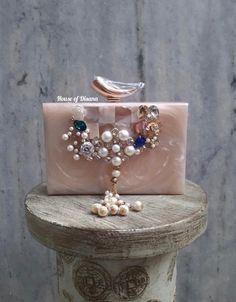 This statement Crystals embellished resin clutch is an true example of elegance. It comes with stones embellishments and a metal sling chain. Details  - Satin lining on the inside to keep your belongings safe  - Magnetic lock closure   - Removable sling chain - Designer metal knob  This clutch can be worn as a shoulder bag with the sling chain or can simply be carried in hand.It is spacious enough to carry mobile phones, lipsticks, Keys and other small accessories.It comes in dust cover placed i Traditional Clutch With Pearl Handle As Gift, Traditional Clutch With Pearl Handle For Formal Events, Traditional Clutch With Pearl Handle For Formal Occasions, Traditional Evening Clutch With Pearl Handle, Traditional Formal Clutch With Pearl Handle, Hand Embellished Rectangular Clutch For Gift, Embellished Rectangular Clutch As Gift, Pearl Embellished Clutch Evening Bag As Gift, Rectangular Embellished Clutch As Gift