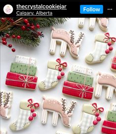 christmas cookies decorated like stockings and deers on a white table with red berries, pine cones and evergreen branches