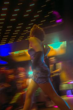 a blurry image of a woman dancing in the dark with neon lights behind her