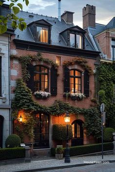 an old brick building with ivy growing all over it's windows and shutters