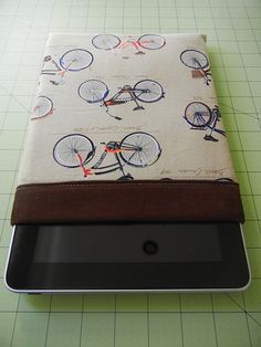 an ipad case sitting on top of a piece of paper with bicycles printed on it