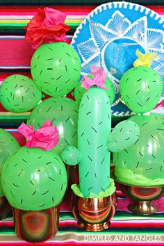 green cactus decorations are on display in front of a mexican themed tablecloth and plates