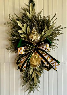 a wreath hanging on the side of a wall with ribbons and bells attached to it