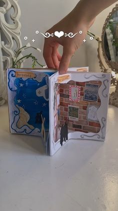 someone is opening the inside of a small book with pictures and words on it,