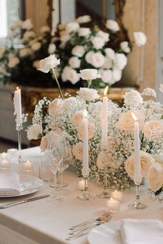 the table is set with white flowers and candles