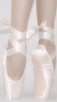 the feet of a ballerina in white ballet shoes with ribbons tied around their ankles