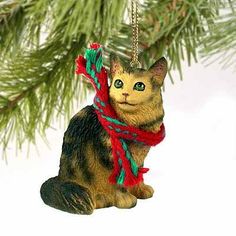 a cat ornament hanging from a christmas tree with a red scarf around it's neck