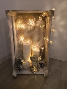 a lighted box with candles and pine cones