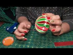 a woman is working on an ornament with red and green decorations