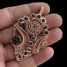 a hand holding a rose shaped brooch with black stones in it's center